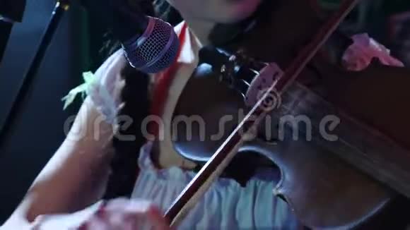 女小提琴家的特写镜头在黑暗的背景下热情地在室内演奏小提琴弦乐器视频的预览图