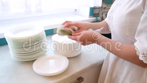 一个穿白色连衣裙的女孩用毛巾擦拭盘子视频的预览图
