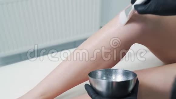 医生双手在激光脱毛前将特殊凝胶涂于女性腿部视频的预览图