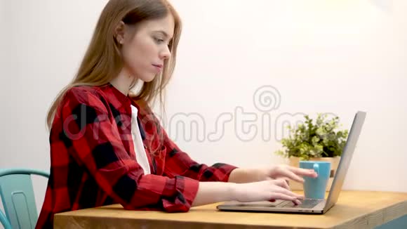 一个年轻的女性可以是一个年轻的企业家也可以是一个学生或者一个作家正坐在一台普通的笔记本电脑上工作视频的预览图