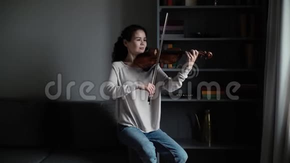 美丽的年轻女子小提琴手在家中缓慢地演奏小提琴视频的预览图