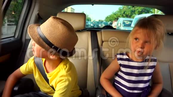 小男孩和小女孩正从车后座的车窗里看着视频的预览图