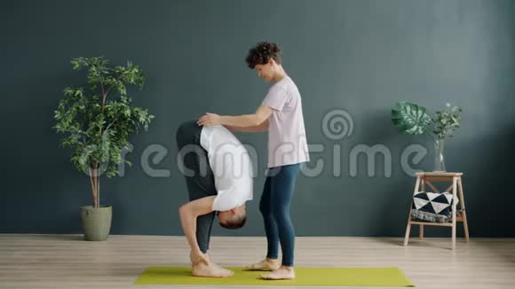 瑜伽老师和女学生在健身房做双人瑜伽女生举重男生聊天视频的预览图