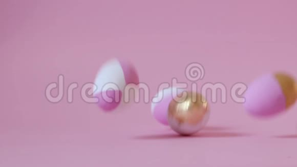 快乐复活节的概念多种颜色的粉红色金蛋落在粉红色的背景上视频的预览图