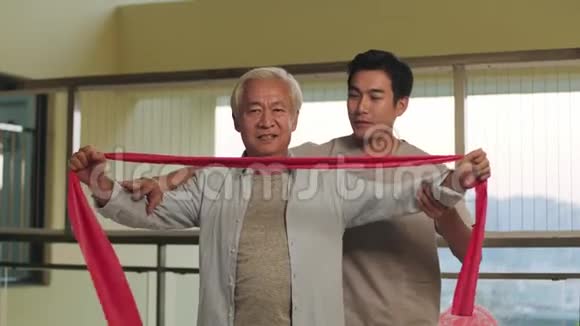 在康复中心使用阻力带锻炼的亚洲老人视频的预览图