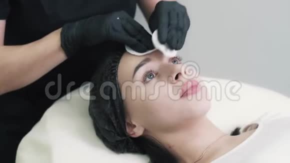 美容师在护理前用棉垫清洁女性面部皮肤视频的预览图