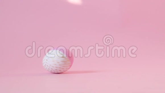 装饰着金色和粉色颜料的木蛋在粉色的背景上旋转复活节快乐的概念蛋在旋转视频的预览图