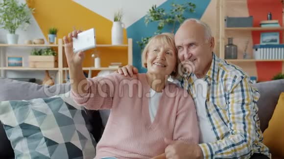 一对夫妇在家里用智能手机拍照自拍视频的预览图