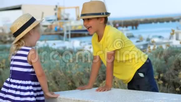 戴帽子的小男孩和小女孩正在游艇码头上玩耍视频的预览图