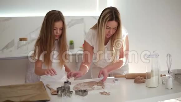 母亲和女儿都留着长发从厨房的面团里剪出不同的饼干形状妈妈和女儿视频的预览图