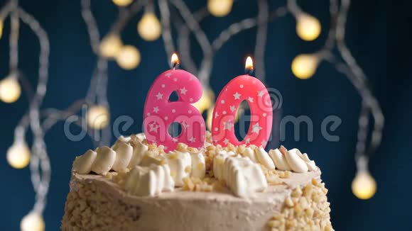 生日蛋糕上面有60个数字的粉红色燃烧蜡烛在蓝色的背景上蜡烛吹灭了慢速运动和特写镜头视频的预览图