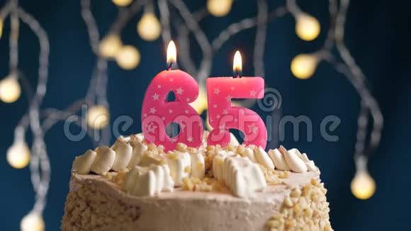 生日蛋糕上面有65号粉红色燃烧的蜡烛在蓝色的背景上蜡烛吹灭了慢速运动和特写镜头视频的预览图