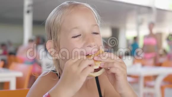 美丽快乐饥饿的女婴吃汉堡包快餐概念手里拿着不健康的汉堡三明治视频的预览图