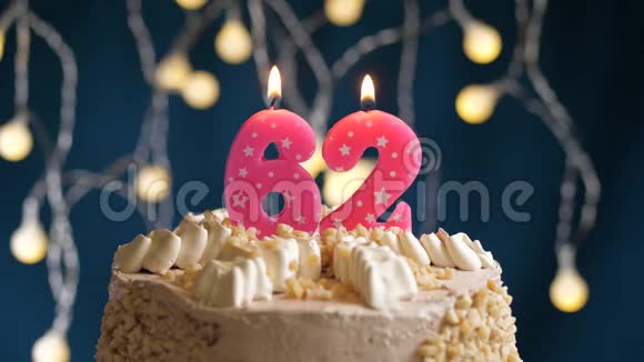 生日蛋糕上面有62个数字粉红色燃烧的蜡烛在蓝色的背景上蜡烛吹灭了慢速运动和特写镜头视频的预览图