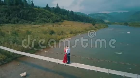 一对夫妇站在一条山河上的桥上对男人和女人的爱视频的预览图