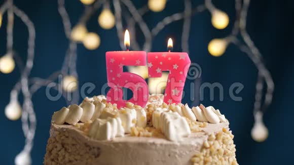 生日蛋糕上面有57个粉红色的燃烧蜡烛在蓝色的背景上蜡烛吹灭了慢速运动和特写镜头视频的预览图