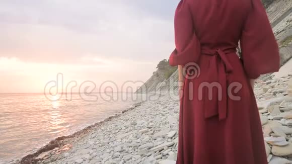 太阳落山时一个赤脚女孩穿着一件红色的裙子在风中飘动她的腿后面做了一个动作视频的预览图