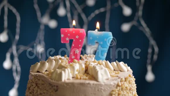 生日蛋糕上有77个数字的粉红色燃烧蜡烛在蓝色的背景上蜡烛吹灭了慢速运动和特写镜头视频的预览图
