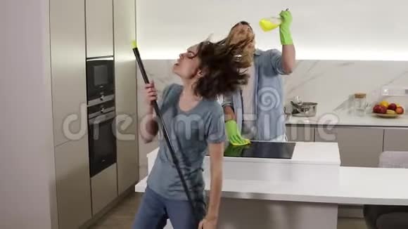 两个年轻人一起跳舞用扫帚和清洁工具当麦克风唱歌视频的预览图