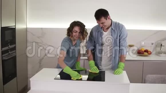 用四只手清洁厨房的烹饪面板年轻的男人和女人清理完美的表面视频的预览图