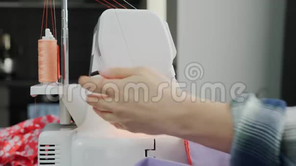 女人在缝纫机上缝制连衣裙把女性的双手紧紧地缝在锁上缝纫面料车间创造和裁剪视频的预览图