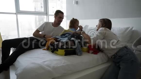 年轻的一家人在打包度假时玩得很开心卧室里有白人男人女人和孩子小孩坐在里面视频的预览图