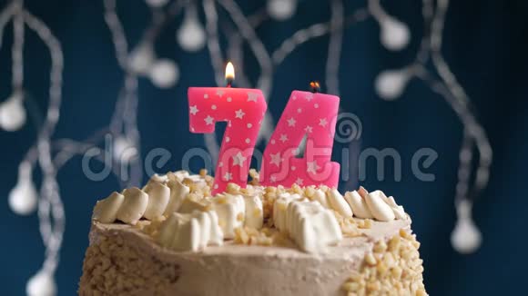 生日蛋糕74号粉红色燃烧的蜡烛在蓝色的背景上蜡烛吹灭了慢速运动和特写镜头视频的预览图
