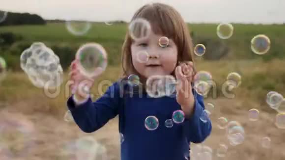 可爱的小女孩在户外玩捉肥皂泡视频的预览图