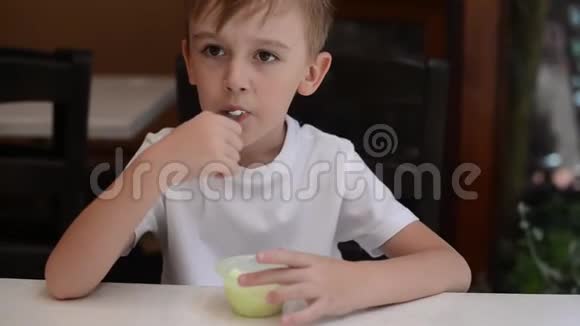 可爱的男孩在咖啡馆露台吃冰淇淋开心的孩子一边吃冰淇淋一边笑视频的预览图