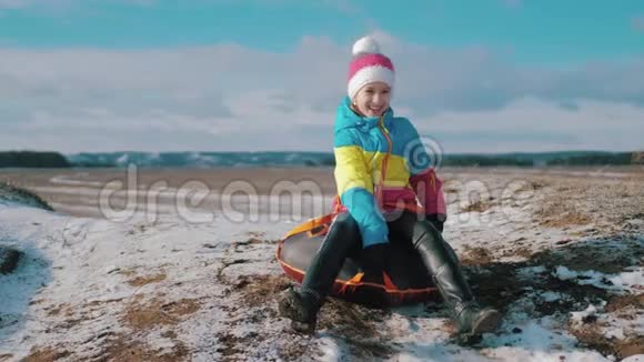 年轻女孩骑在一座小山上的充气雪管上视频的预览图