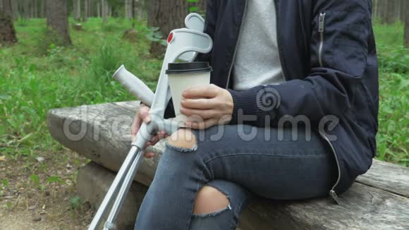 拄着拐杖的残疾女性在长凳上拿走咖啡视频的预览图