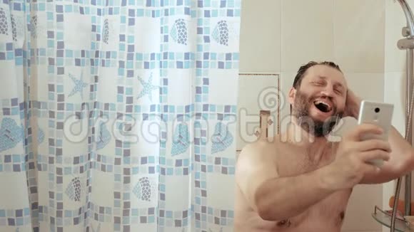 洗澡的大胡子男人手里拿着电话看新闻他很高兴笑了慢动作视频的预览图