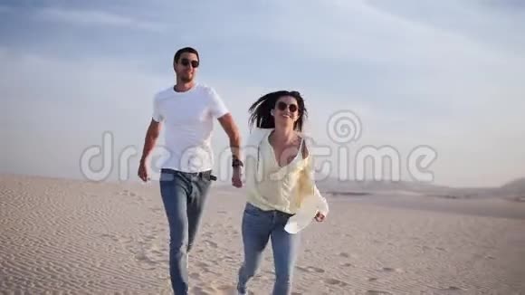 一对情侣牵着手在阳光下嬉戏在阳光下浪漫在沙漠中蓝天视频的预览图