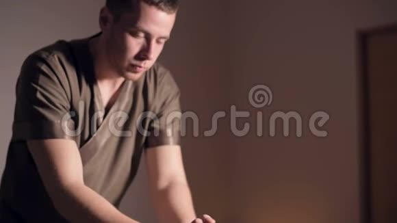年轻的男性按摩治疗师在按摩室里给一个纹身的女人做背部按摩视频的预览图