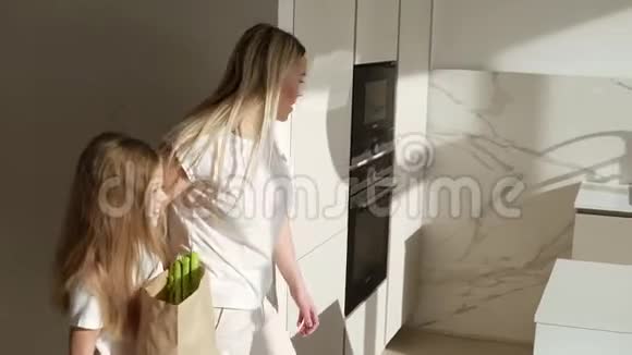 金发白种人的母亲带着女儿上厨房来购物从健康的有机食品中取出大棕色纸袋视频的预览图