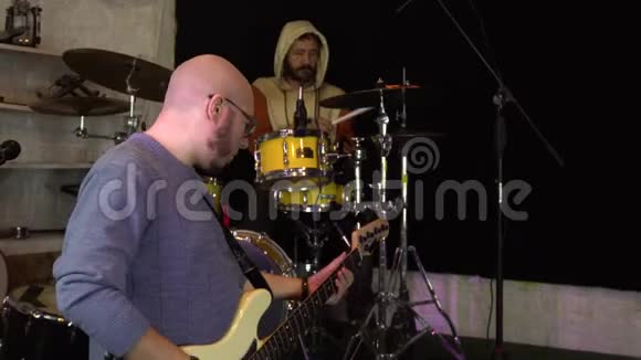 吉他手和鼓手在车库里演奏音乐摇滚乐队练习音乐乐队在录音室表演概念视频的预览图
