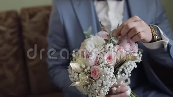家里手里拿着结婚花束的新郎白色衬衫夹克视频的预览图