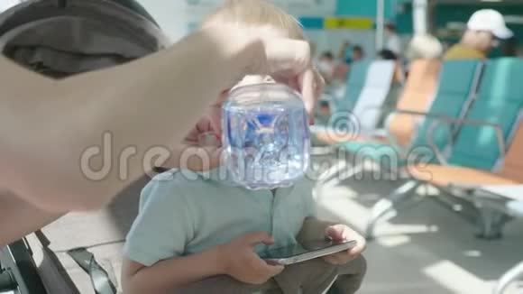 妈妈在机场休息室给一个小儿子喝水视频的预览图