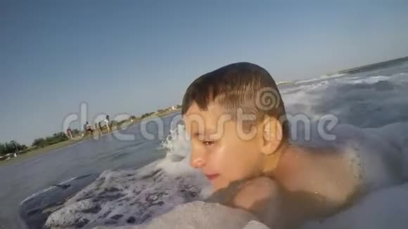 冲浪板上游泳的男孩在向海岸泼水视频的预览图