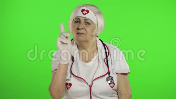 戴防护面罩的老年白种人女医生挥舞着她的手警告视频的预览图