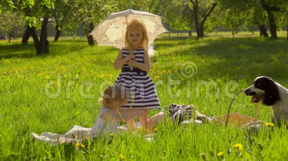 三个女孩正坐在花园的草坪上撑着老式的太阳伞视频的预览图