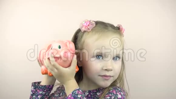 一个小女孩摇着储蓄罐听到硬币的声音视频的预览图