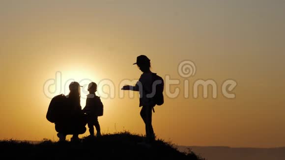 母亲和两个孩子在日落时剪影友好家庭观念视频的预览图