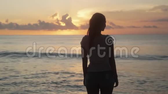 背面的景色女人的轮廓看海洋日落张开双臂视频的预览图
