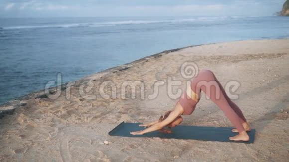 穿着舒适运动服的女孩在沙滩上做瑜伽视频的预览图