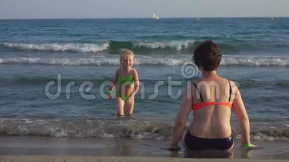 穿着泳衣的妈妈和女儿在海滨拥抱视频的预览图
