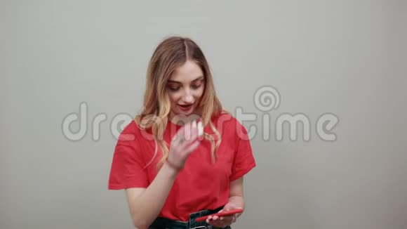漂亮的年轻女子穿着红色衬衫带着电话看着它视频的预览图