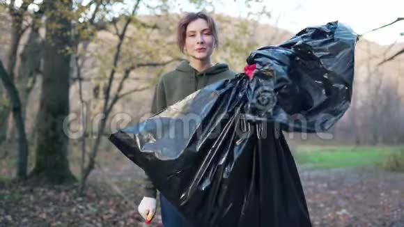 一位美丽的志愿者女人手里拿着垃圾袋的肖像开展一次清理森林的运动视频的预览图
