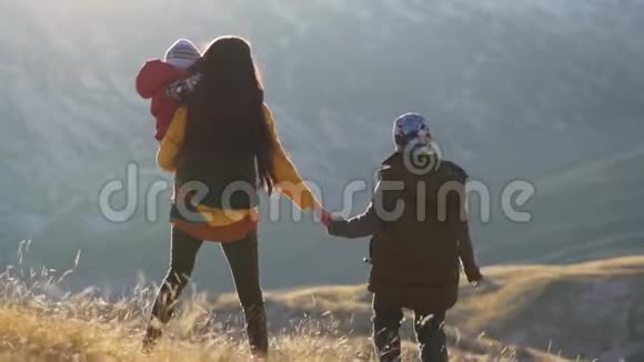 单身母亲带着孩子牵手遇见夕阳背光灯视频的预览图