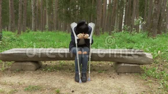 残疾女性拄着拐杖坐在长椅上在公园里哭泣视频的预览图